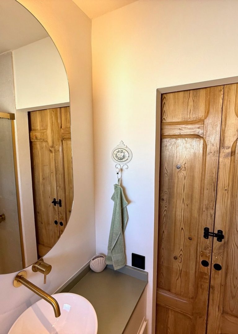 Dormitorio acogedor con cama, ventanas de madera y decoración moderna en tonos claros.