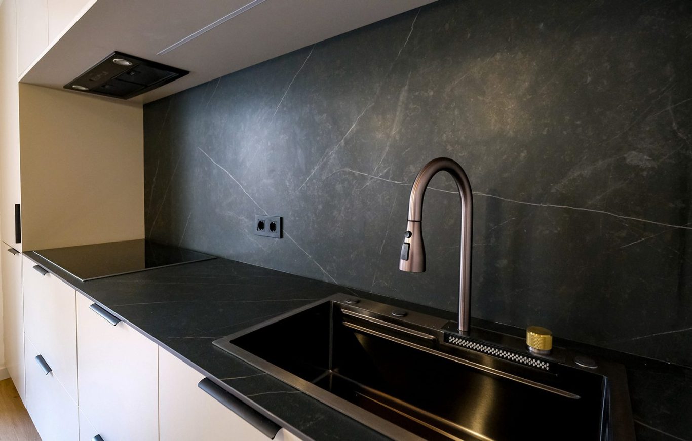 Fregadero moderno de acero inoxidable en una cocina con encimera oscura.