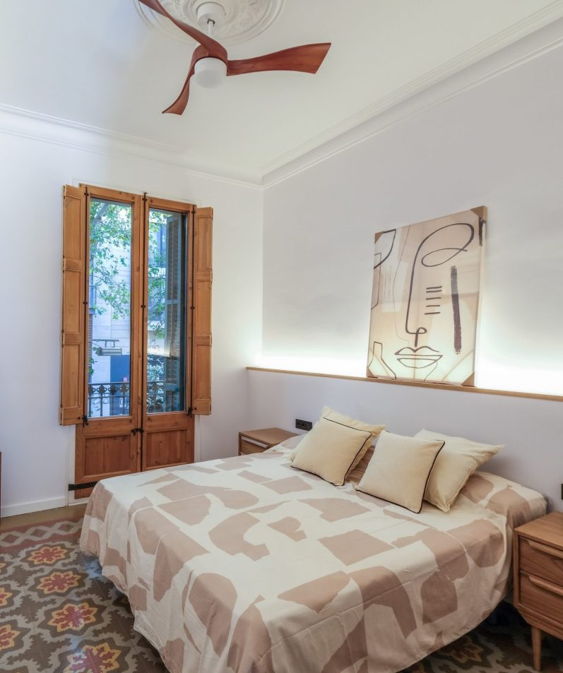 Dormitorio acogedor con cama, ventanas de madera y decoración moderna en tonos claros.