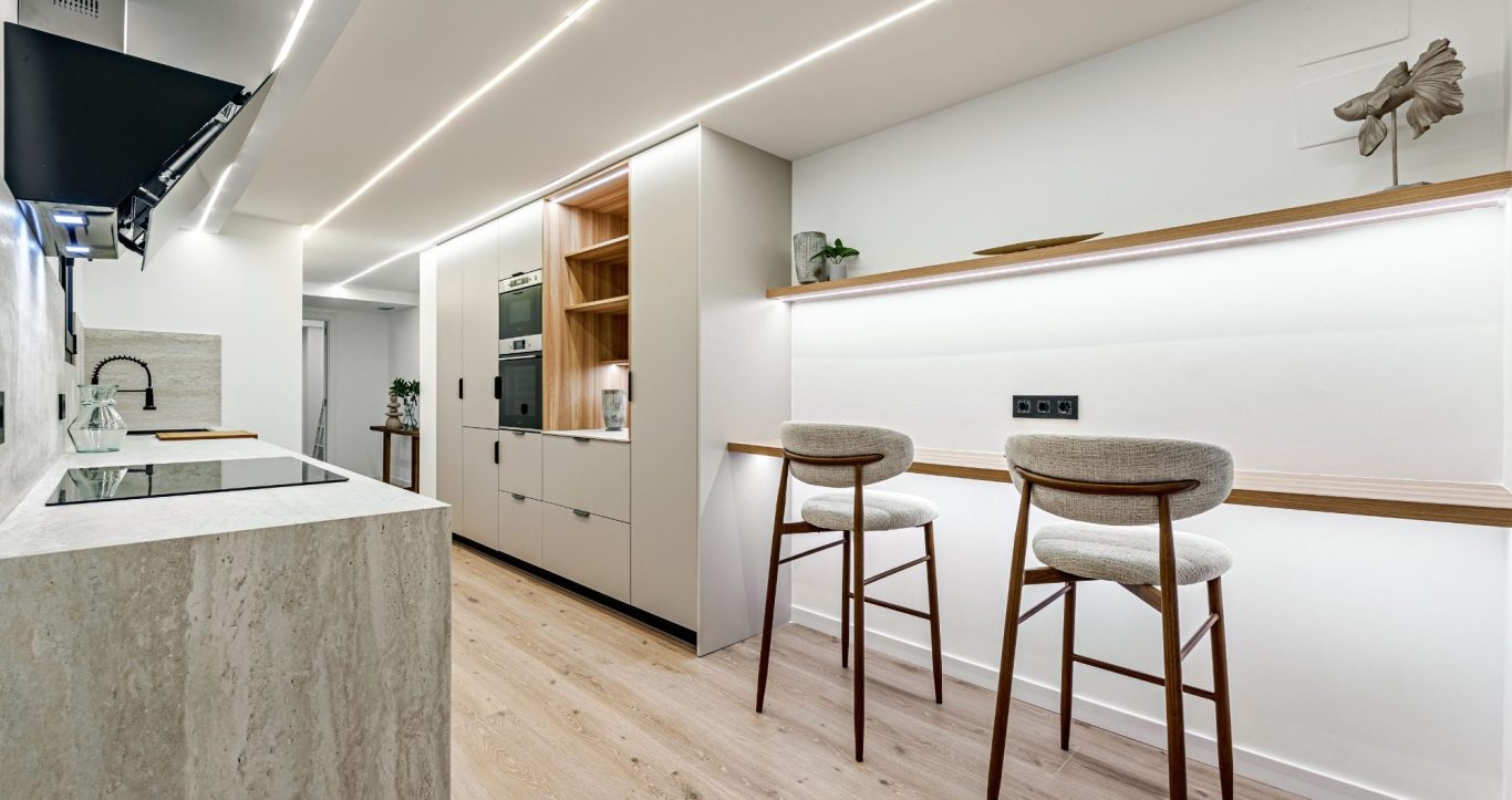 Cocina moderna con barra de desayuno, muebles claros y luz ambiental.