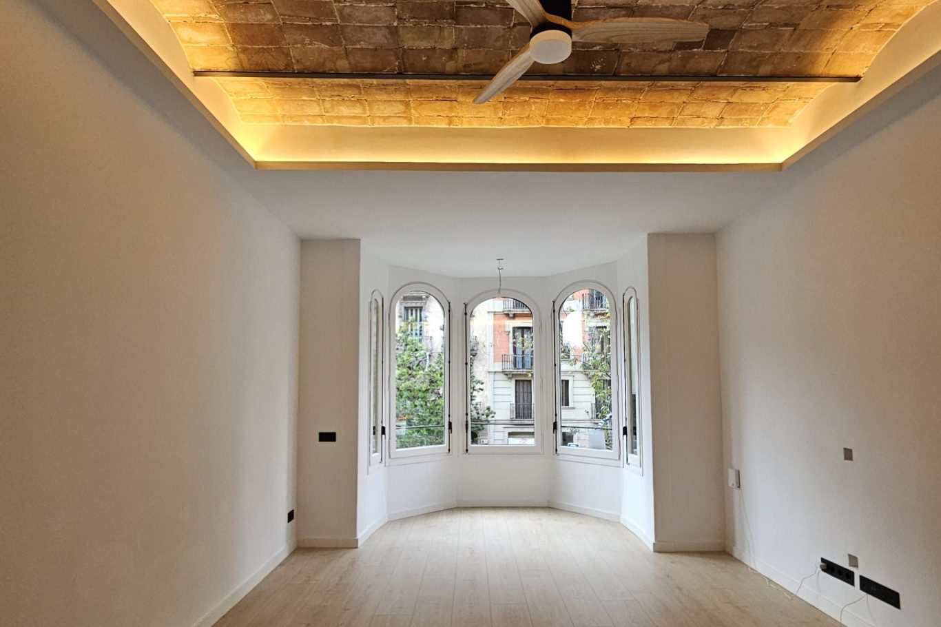 Sala con pared clara, mueble bajo y espejo antiguo en un ambiente minimalista.