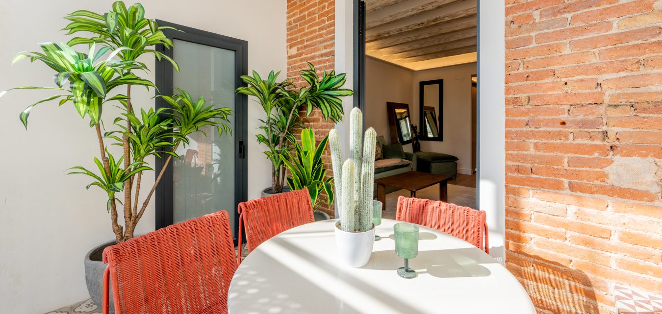 Sofá blanco en un patio moderno, con mesa de café y planta decorativa al fondo.
