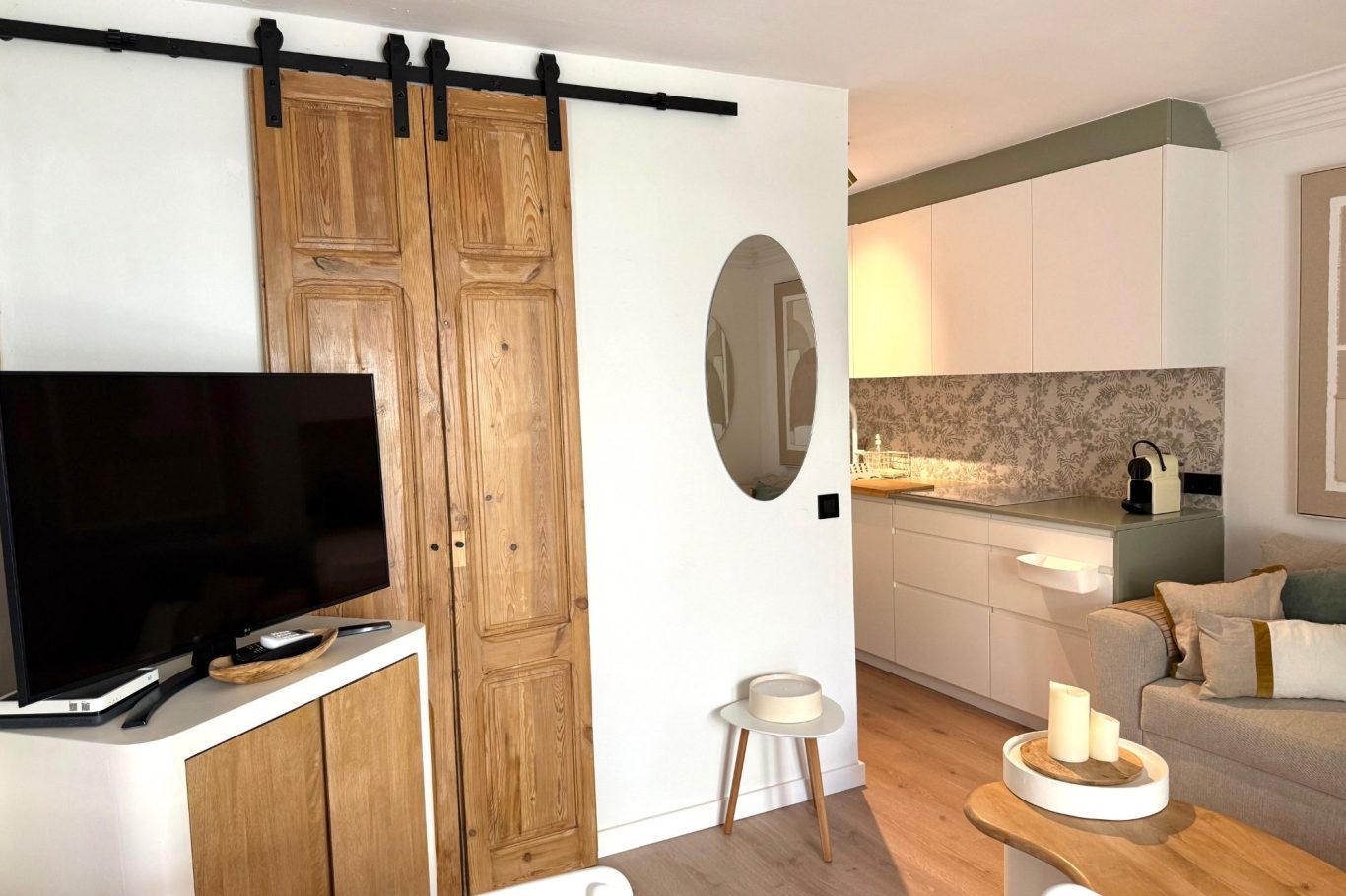 Sala con pared clara, mueble bajo y espejo antiguo en un ambiente minimalista.