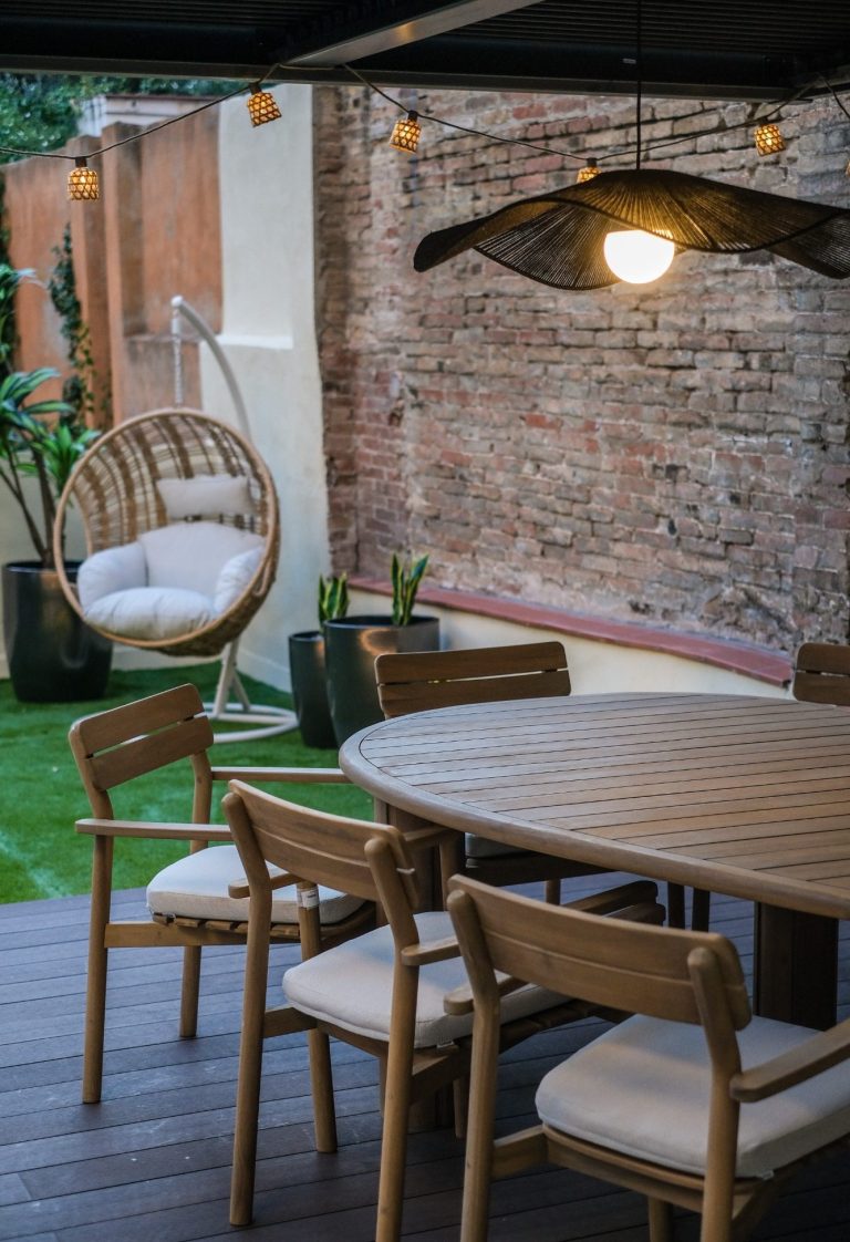 Terraza con muebles de madera, sillas, mesa redonda y una hamaca colgante.