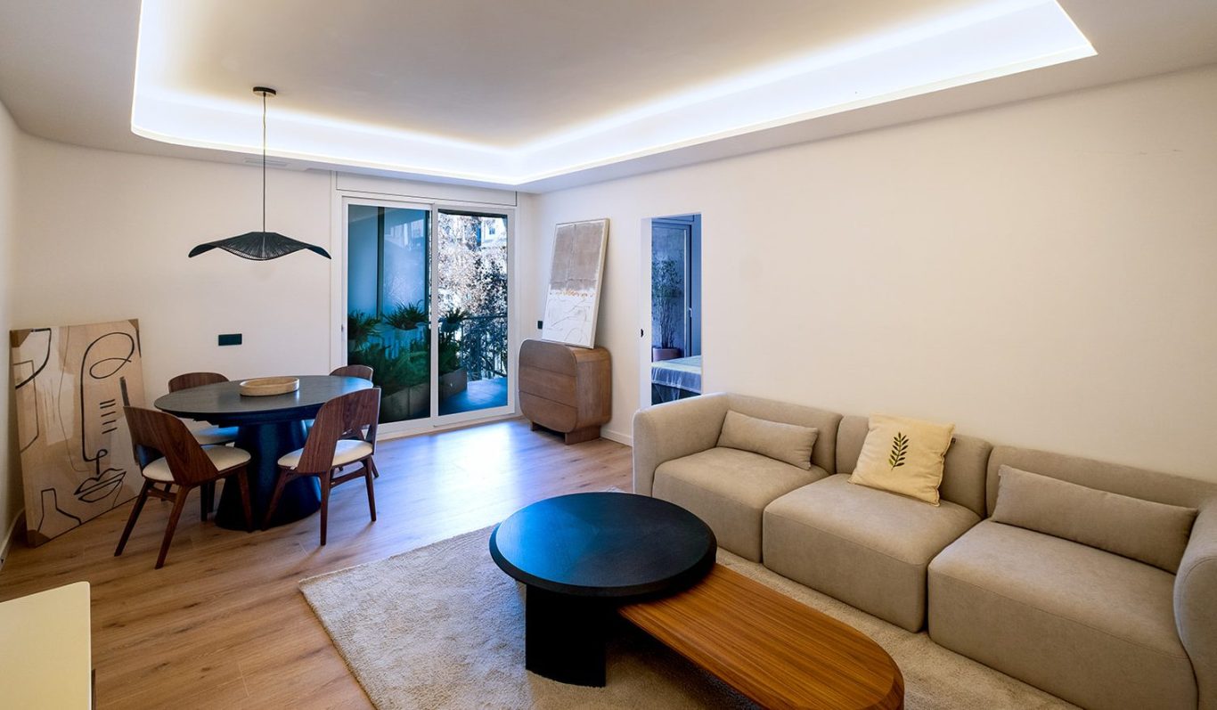 Sala de estar moderna con sofá, mesa de comedor y acceso a un balcón. Decoración minimalista.