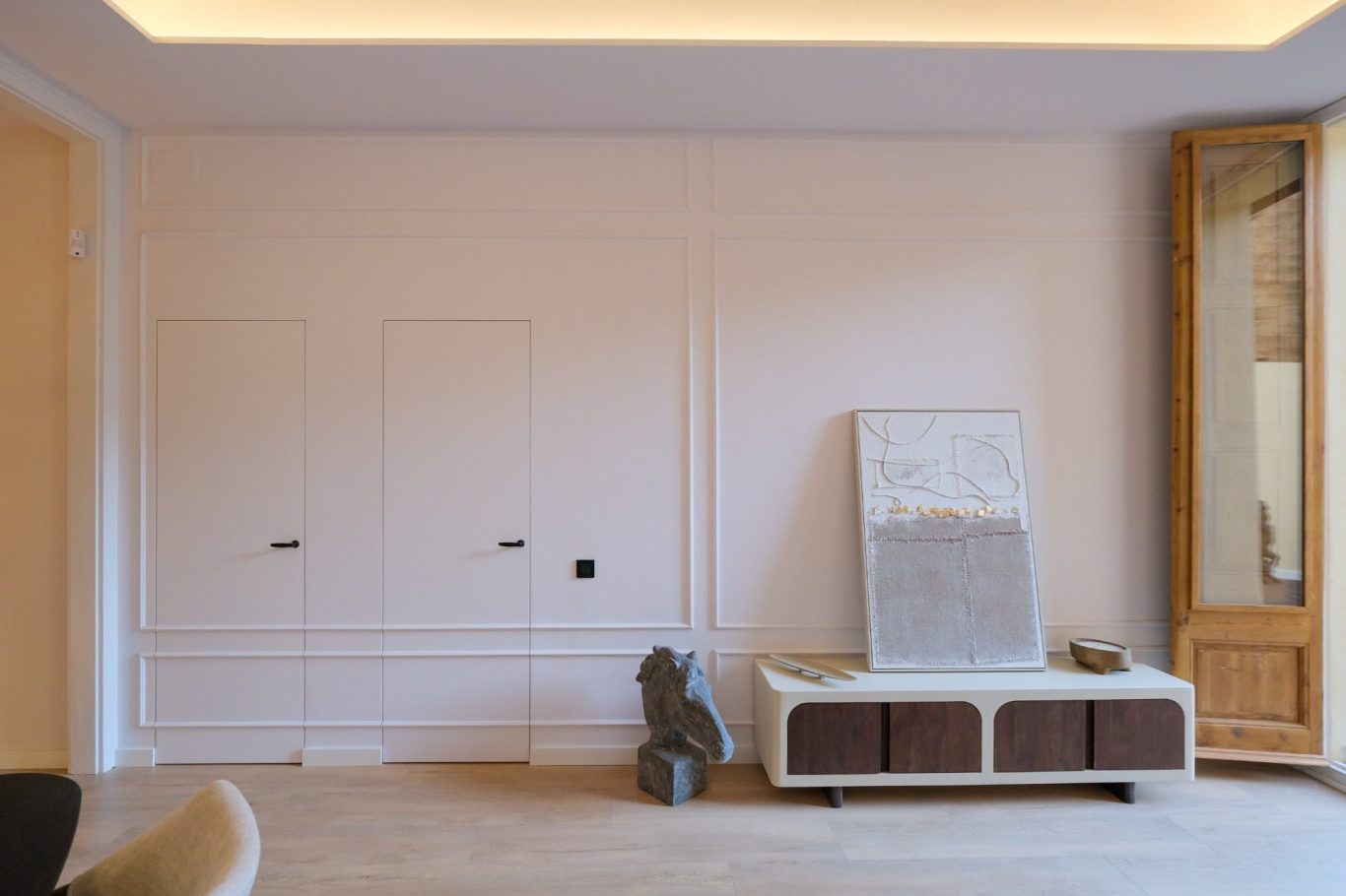 Sala con pared clara, mueble bajo y espejo antiguo en un ambiente minimalista.