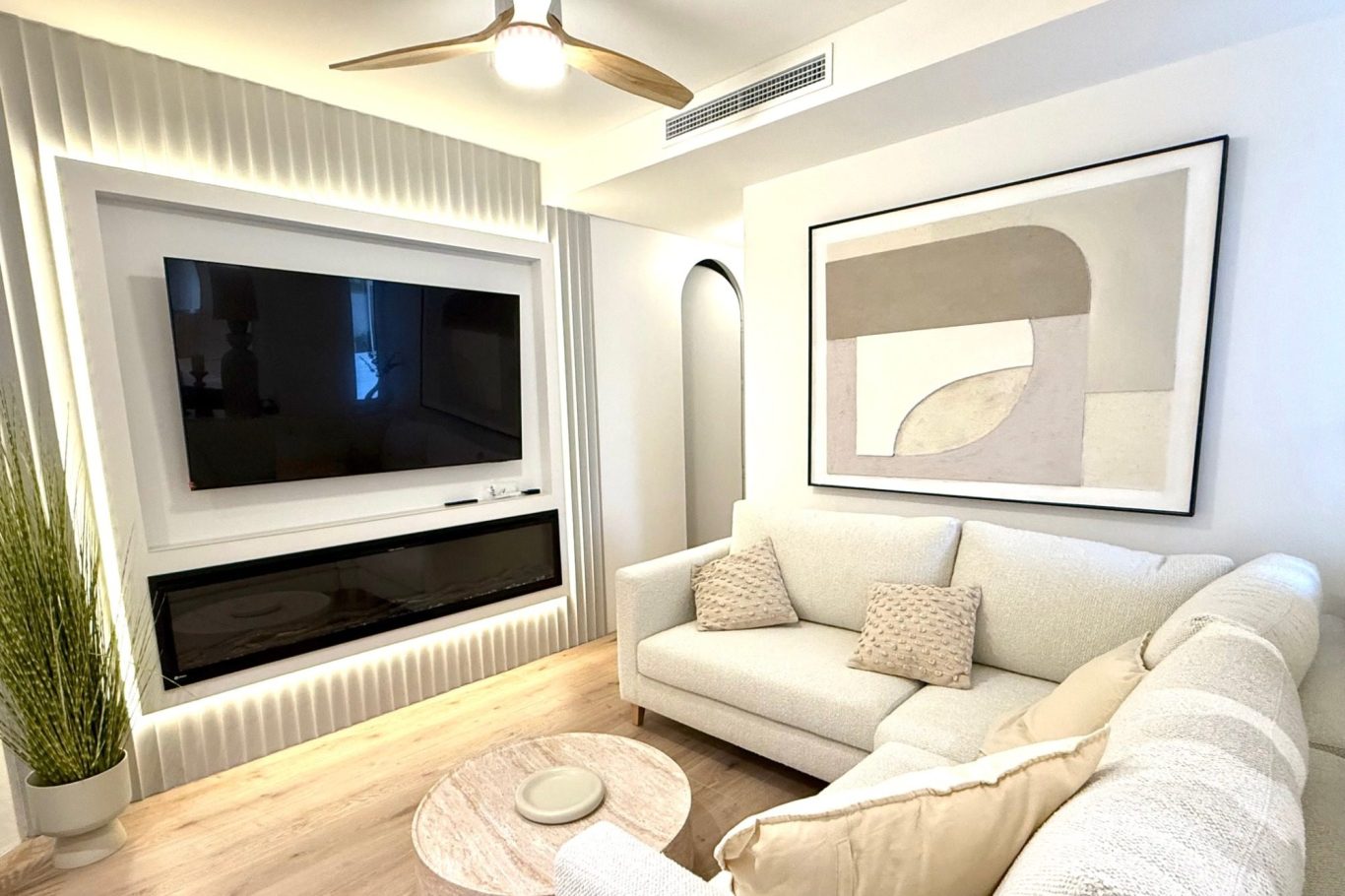 Sala con pared clara, mueble bajo y espejo antiguo en un ambiente minimalista.
