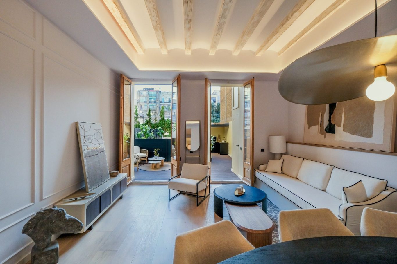 Sala de estar luminosa con sofá, mesa de café y acceso a un balcón. Decoración moderna y acogedora.