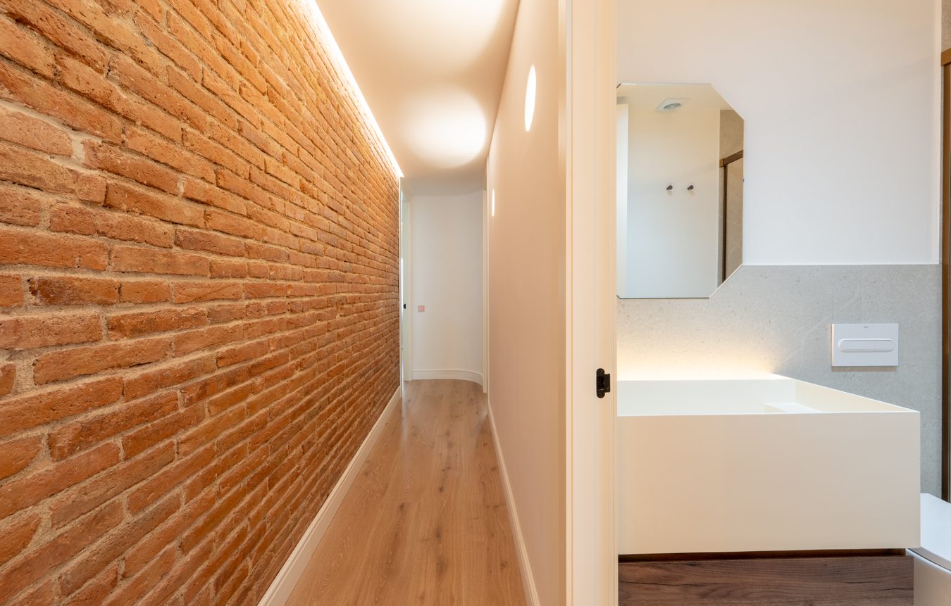 Baño moderno con lavabo de piedra, espejo circular y ducha con iluminación suave.
