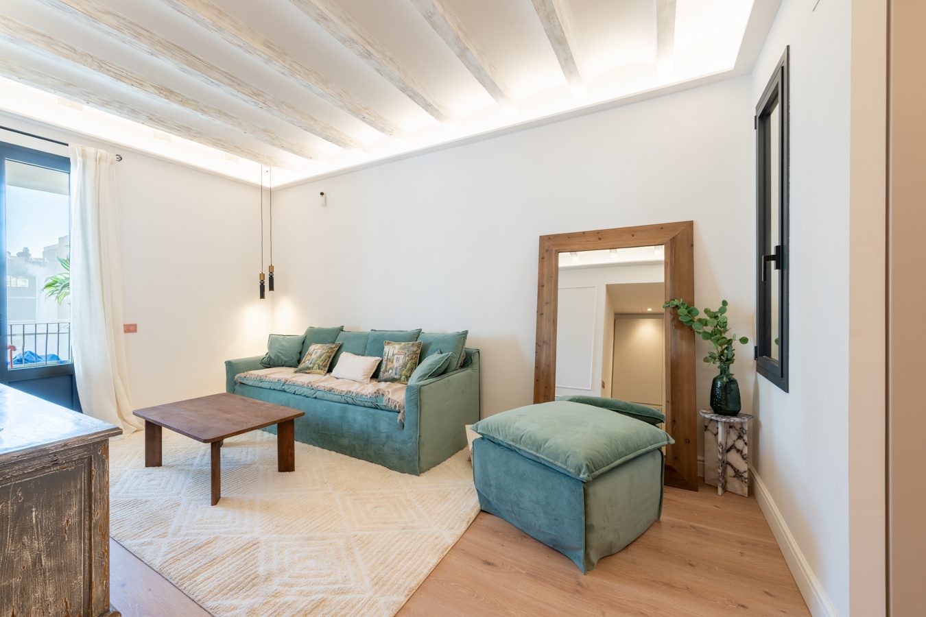 Sala de estar luminosa con sofá, mesa de café y acceso a un balcón. Decoración moderna y acogedora.