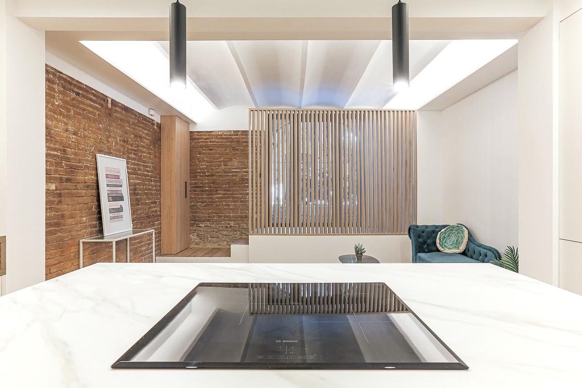 Sala con pared clara, mueble bajo y espejo antiguo en un ambiente minimalista.