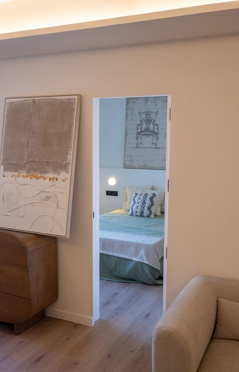 Vista de un dormitorio a través de una puerta en una sala de estar moderna y minimalista.