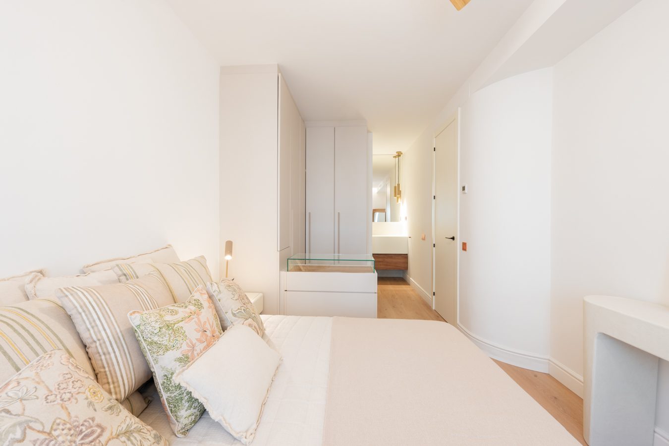 Dormitorio acogedor con cama, ventanas de madera y decoración moderna en tonos claros.