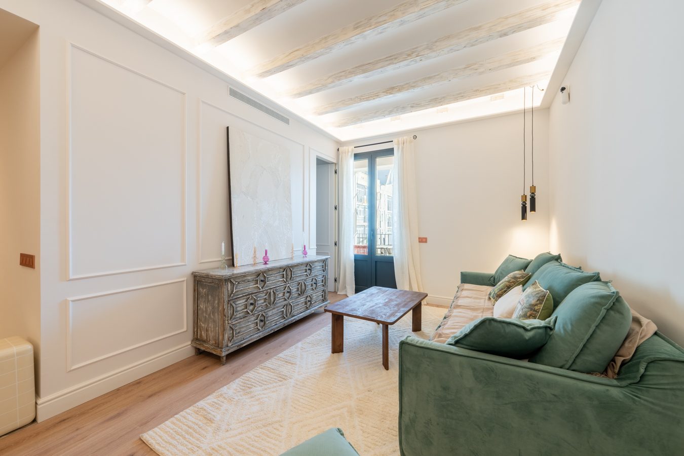 Sala con pared clara, mueble bajo y espejo antiguo en un ambiente minimalista.