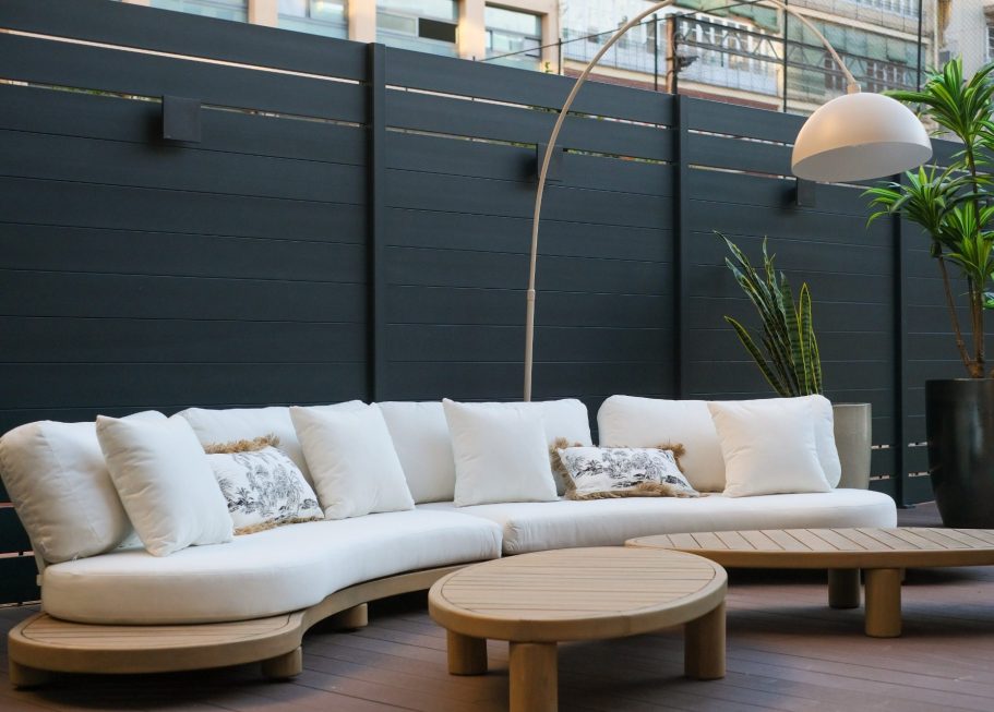 Sofá blanco en un patio moderno, con mesa de café y planta decorativa al fondo.