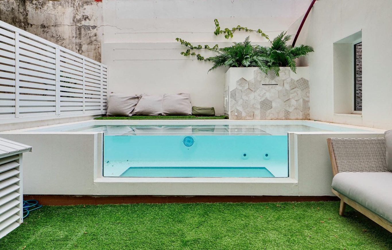 Jardín moderno con tumbonas, plantas y mobiliario en un ambiente urbano.