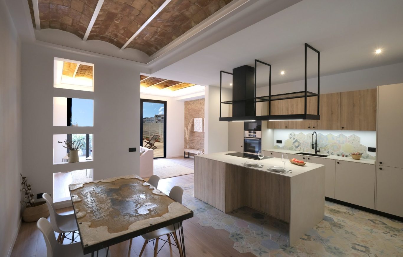 Cocina moderna con muebles de madera, mesa y luz natural. Suelo de azulejos decorativos.