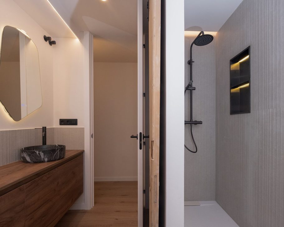 Baño moderno con ducha, lavabo de diseño y paredes de tonos neutros.