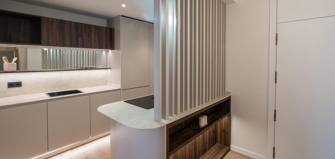 Cocina moderna con armarios oscuros y paneles de madera clara y luces suaves.