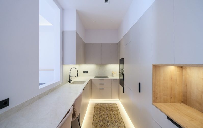 Cocina moderna y minimalista con iluminación cálida y espacio funcional.