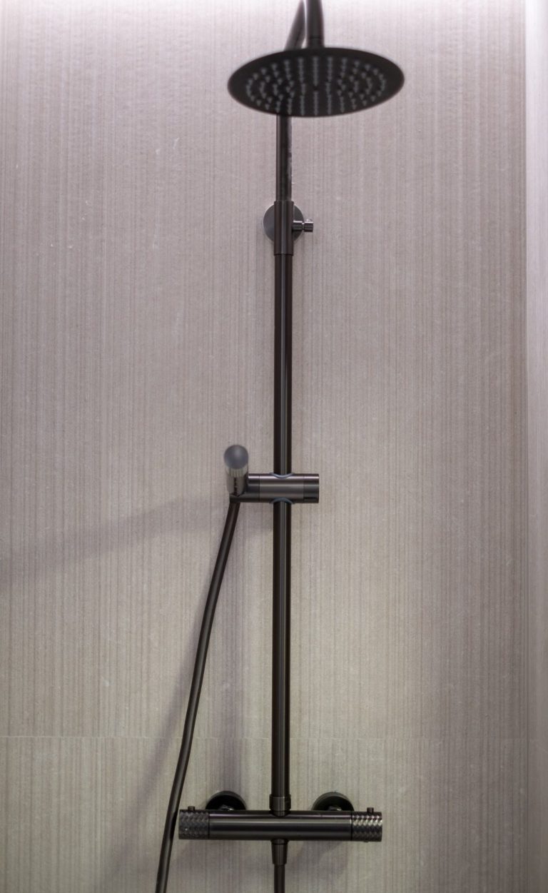 Ducha moderna con cabezal grande y manguera, en un ambiente minimalista.