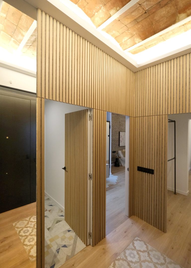 Puerta de madera en un espacio moderno con suelos de madera y azulejos decorativos.