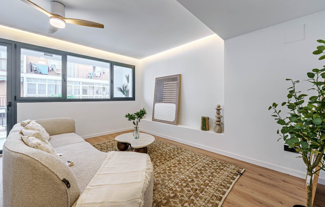 Sala luminosa con sofá blanco, mesa de centro y decoración minimalista.