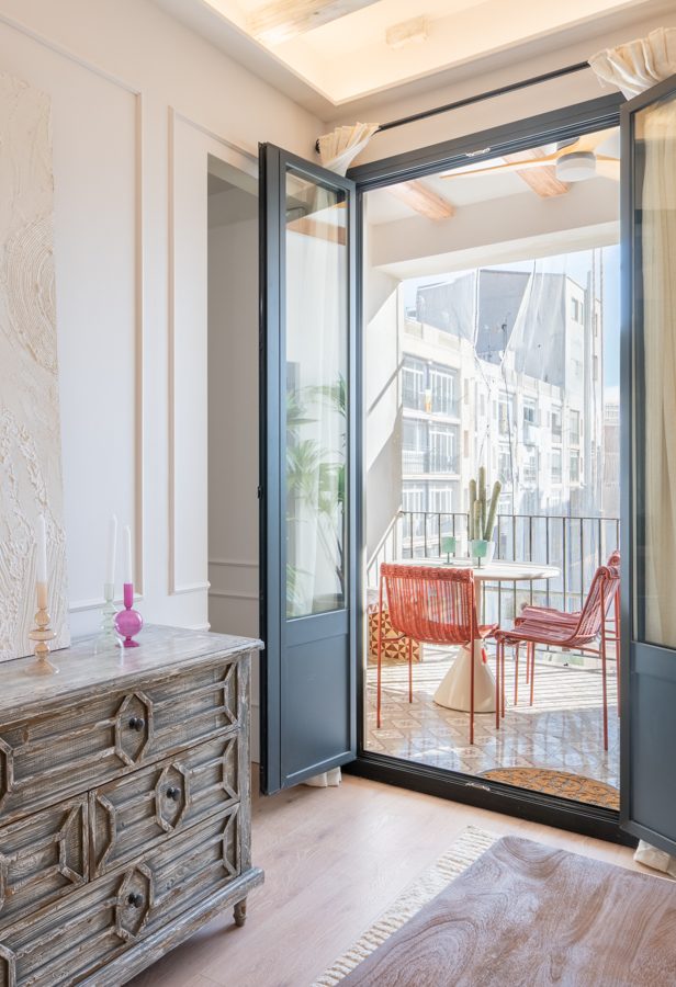 Terraza con muebles de madera, sillas, mesa redonda y una hamaca colgante.