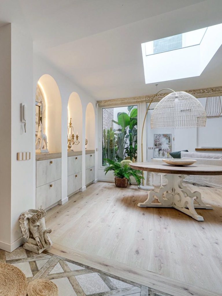Sala comedor moderna con mesa negra y sillas blancas, iluminada con luz suave.