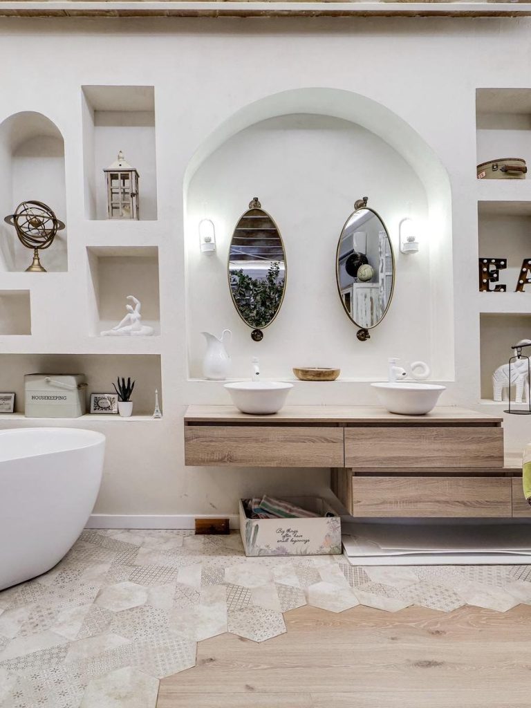 Sofá blanco con cojines, lámpara de luz suave y mesa de centro de madera.